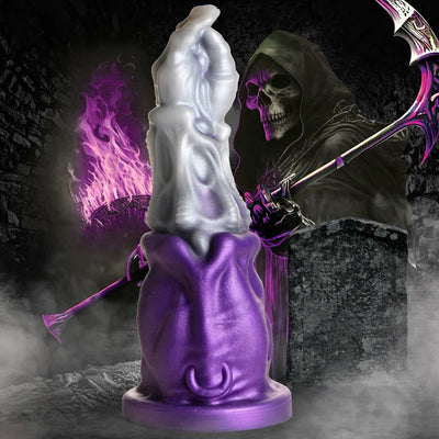 GRIM REAPER SILICON DILDO IN PURPLE AND SILVER FROM CASTLE MEGASTORE WITH THE GROM REAPER IN THE BACKGROUND